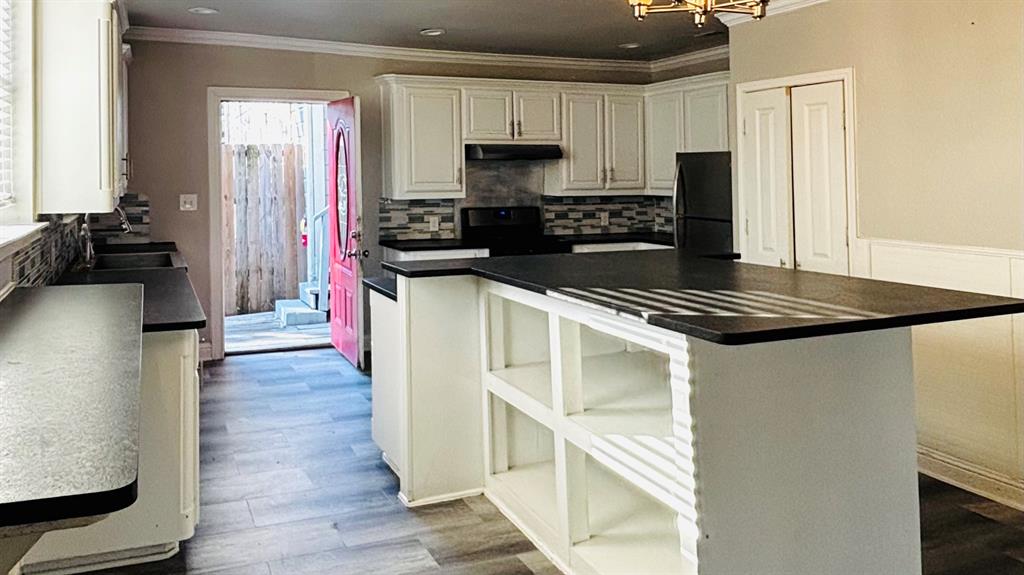 4511 Junius Street Dallas, TX 75246 - Photo 6 of 16 Well-appointed kitchen featuring light-toned cabinetry, dark countertops, and a mosaic tile backsplash