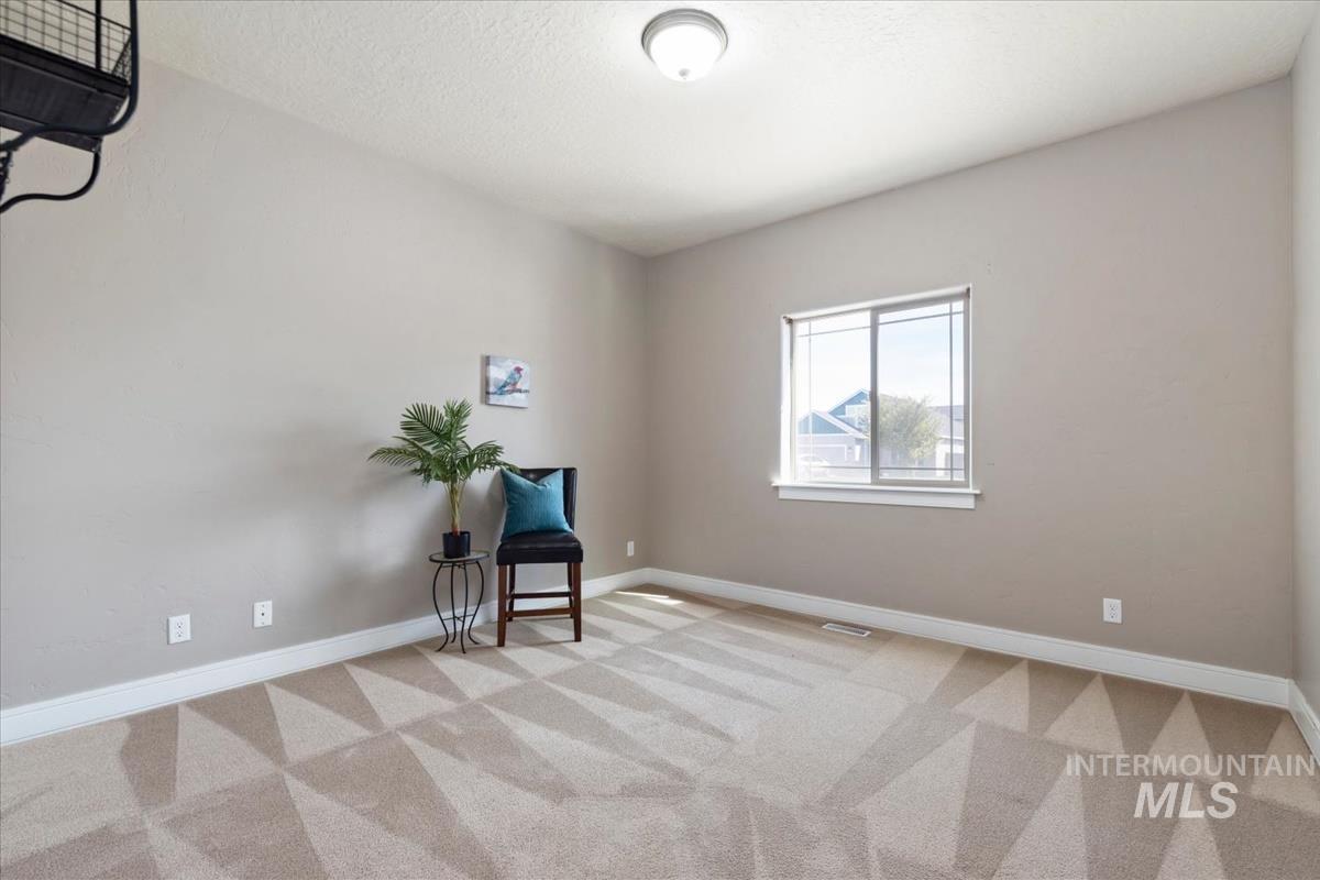 640 Southwest Miner Street Mountain Home, ID 83647 - Photo 6 of 35 Neutral-toned room featuring a large window, patterned carpet, and white baseboards