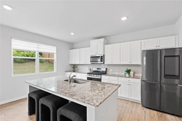 a kitchen with stainless steel appliances granite countertop a sink stove microwave refrigerator and cabinets