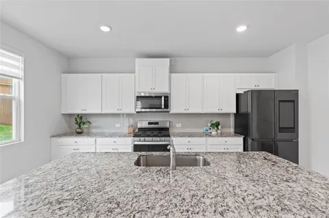 a kitchen with stainless steel appliances granite countertop a stove top oven a sink and a refrigerator