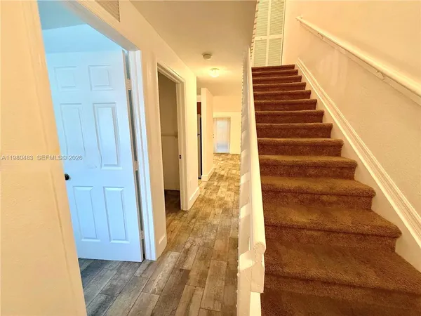a view of a hallway with wooden floor and staircase