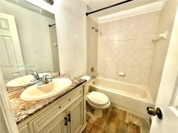 a bathroom with a granite countertop sink toilet mirror and shower