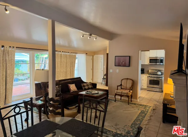 a living room with furniture a flat screen tv and floor to ceiling window