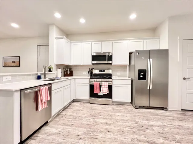 a kitchen with stainless steel appliances a refrigerator and a stove top oven