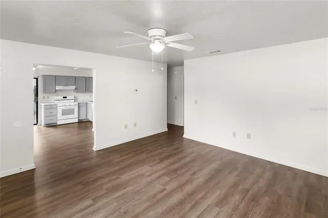 an empty room with wooden floor and ceiling fan