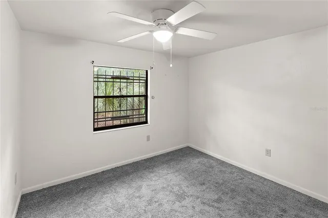 an empty room with a window and ceiling fan