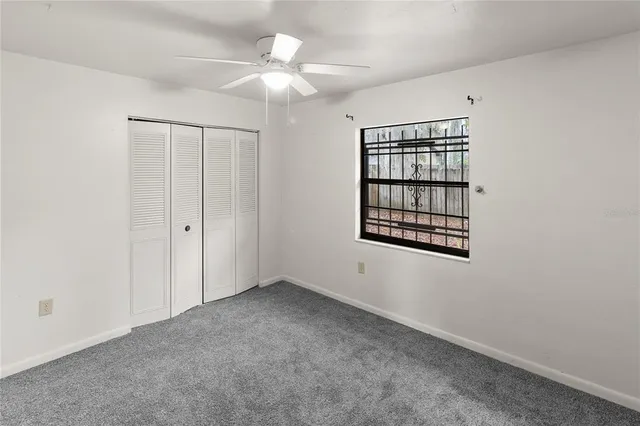 an empty room with windows and fan