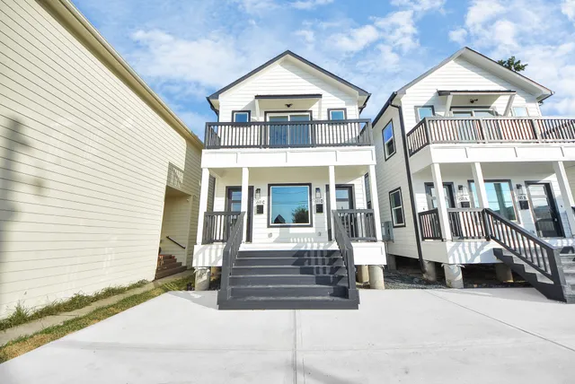 a view of a white house with large windows and a yard
