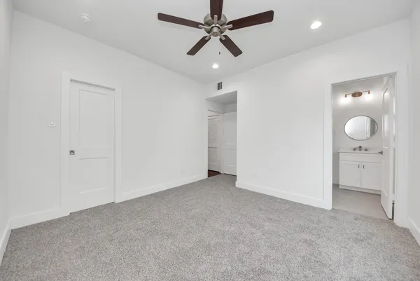 an empty room with windows and ceiling fan