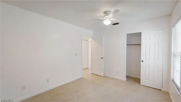 an empty room with a ceiling fan and a window