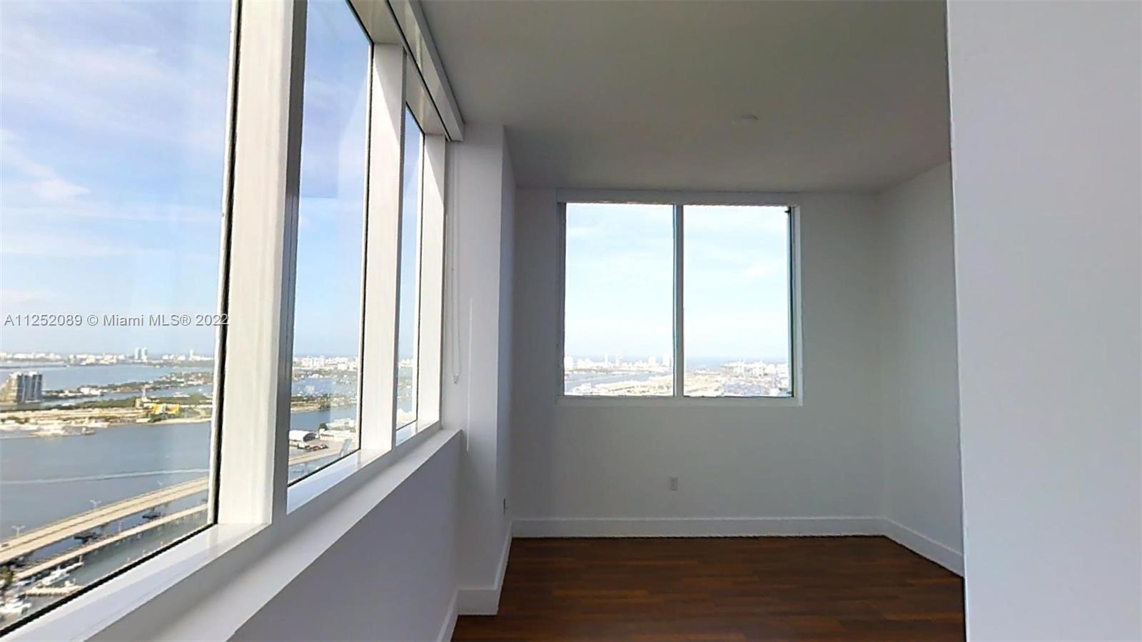 244 Biscayne Boulevard, Unit 4503 Miami, FL 33132 - Photo 27 of 33 an empty room with wooden floor and windows