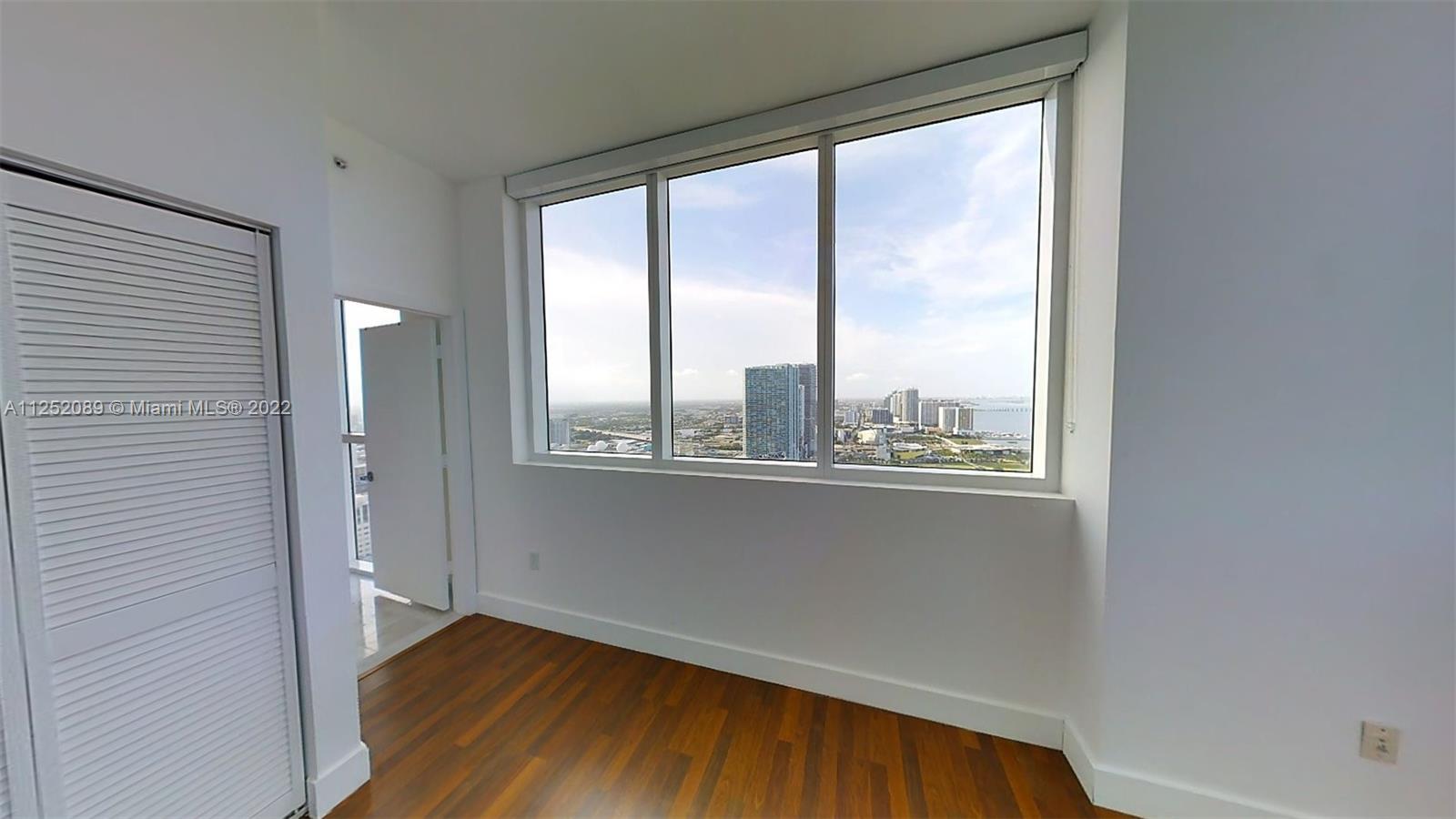 244 Biscayne Boulevard, Unit 4503 Miami, FL 33132 - Photo 31 of 33 a view of a big room with wooden floor and windows