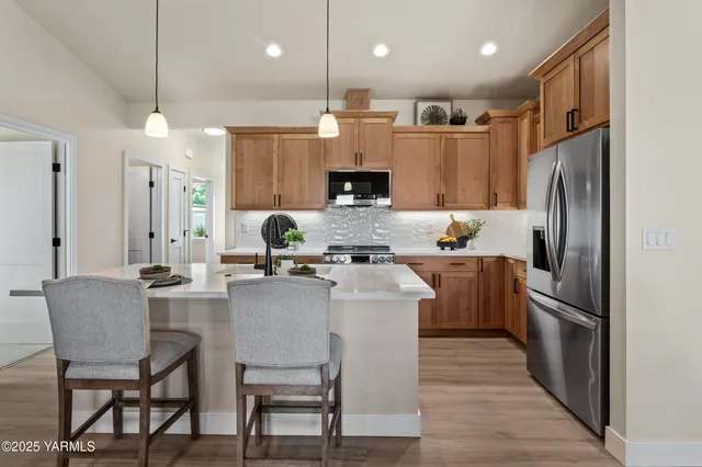 a kitchen with kitchen island a refrigerator a stove a sink and chairs