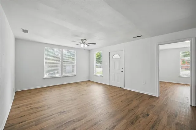 an empty room with wooden floor cabinet and windows