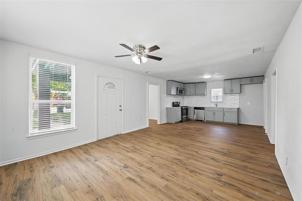 210 North 5th Avenue Denison, TX 75021 - Photo 5 of 20 a view of an empty room with a kitchen and wooden floor