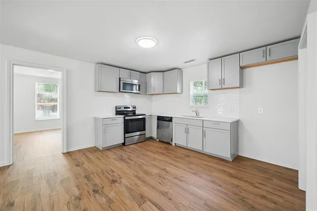a kitchen with granite countertop a sink cabinets and wooden floor