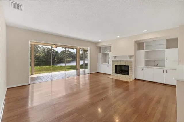 a view of empty room with wooden floor and fireplace