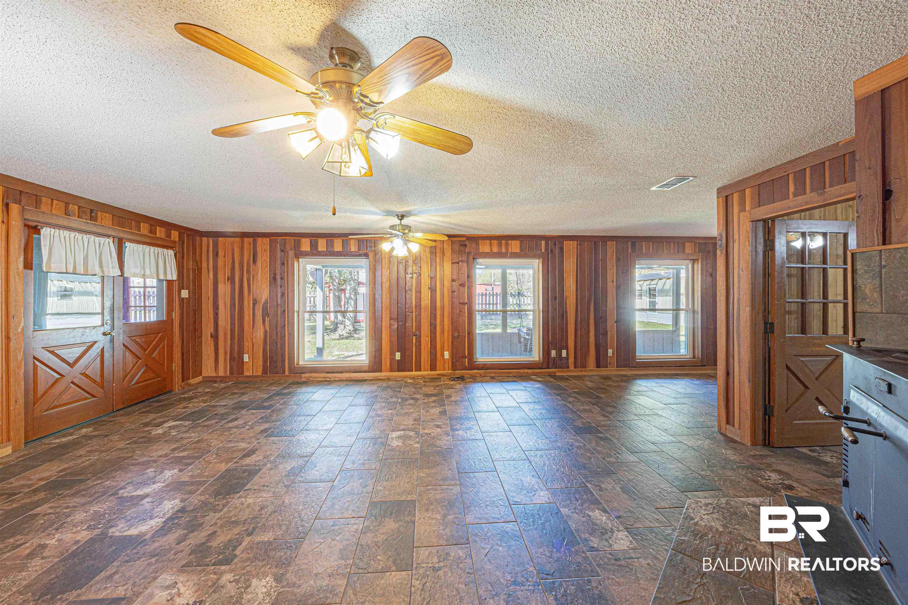 43101 Brown Road Bay Minette, AL 36507 - Photo 13 of 81 Unfurnished dining area with a textured ceiling, wood walls, dark stone finish flooring, and a ceiling fan