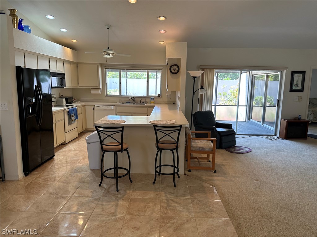 9805 Maplecrest Circle Lehigh Acres, FL 33936 - Photo 2 of 38 a kitchen with a table chairs refrigerator and cabinets