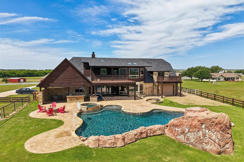 2085 Switzer Road Sanger, TX 76266 - Photo 37 of 39 Expansive outdoor living area featuring a freeform pool with integrated spa, a stamped concrete patio, and a stone facade outdoor kitchen under a covered patio
