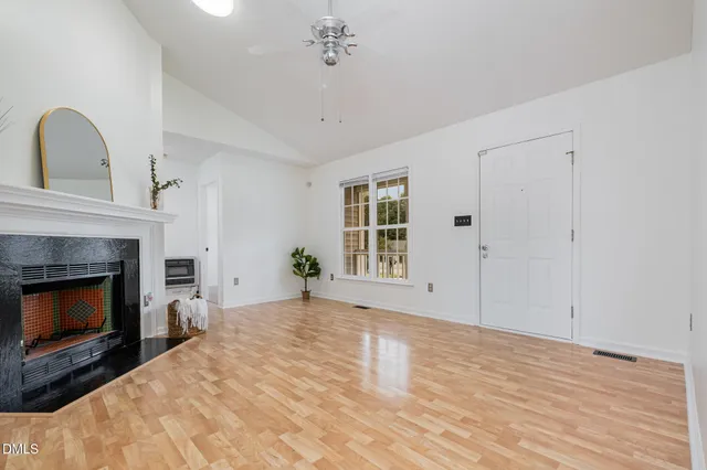 a view of an empty room with wooden floor fireplace and a window