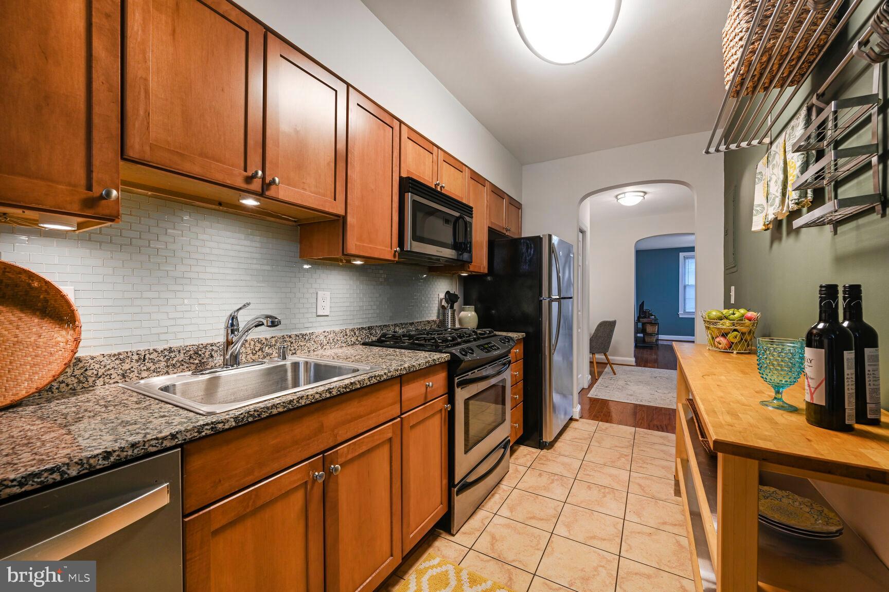6722 3rd Street Northwest, Unit 203 Washington, DC 20012 - Photo 11 of 18 a kitchen with stainless steel appliances granite countertop a sink a stove and a wooden cabinets
