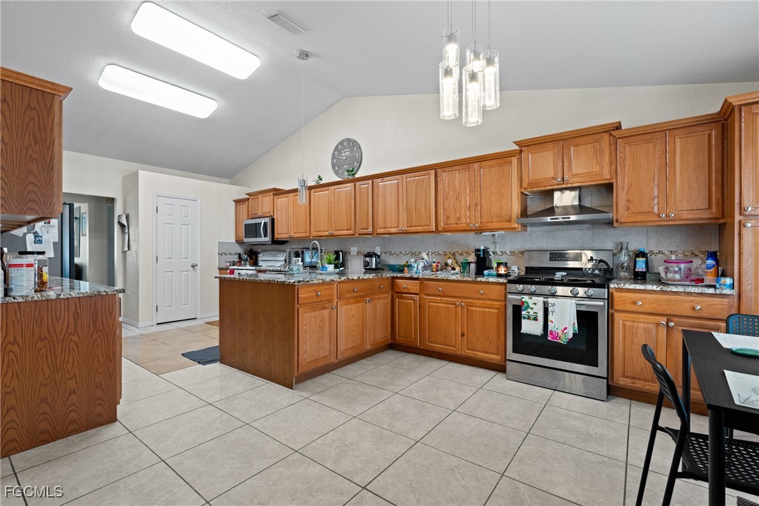609 Gerald Avenue Lehigh Acres, FL 33936 - Photo 17 of 45 a kitchen with stainless steel appliances granite countertop a stove top oven a sink dishwasher and cabinets with wooden floor