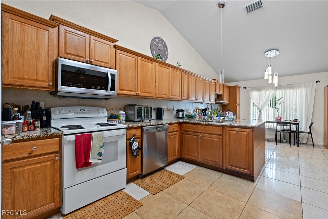 609 Gerald Avenue Lehigh Acres, FL 33936 - Photo 22 of 45 a kitchen with stainless steel appliances granite countertop a stove microwave and cabinets