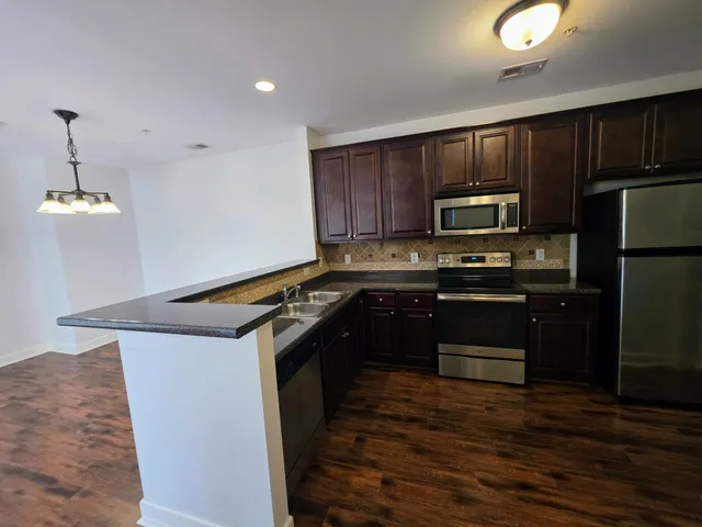a kitchen with kitchen island granite countertop stainless steel appliances and wooden cabinets