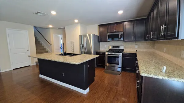 a kitchen with stainless steel appliances granite countertop a stove a sink and a refrigerator