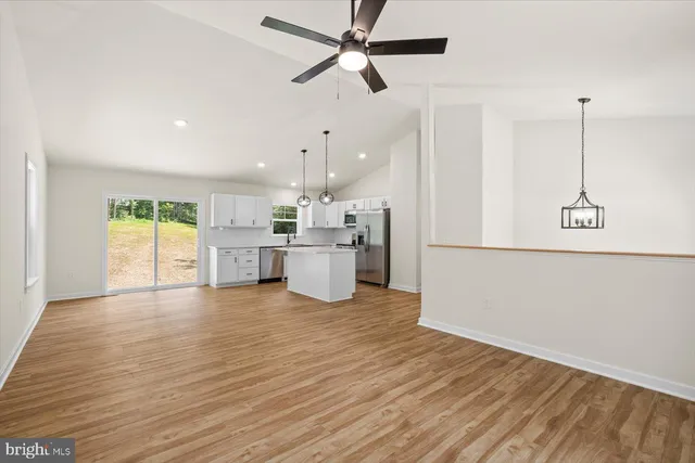 a kitchen with stainless steel appliances kitchen island wooden floors and white cabinets