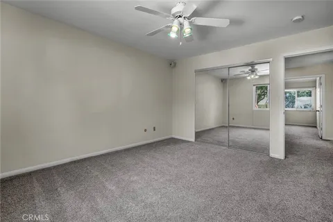 an empty room with chandelier fan and glass door