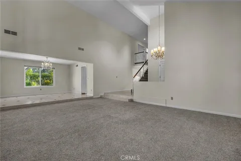 an empty room with a chandelier fan and windows