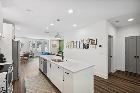 a large white kitchen with a lot of counter space and wooden floor