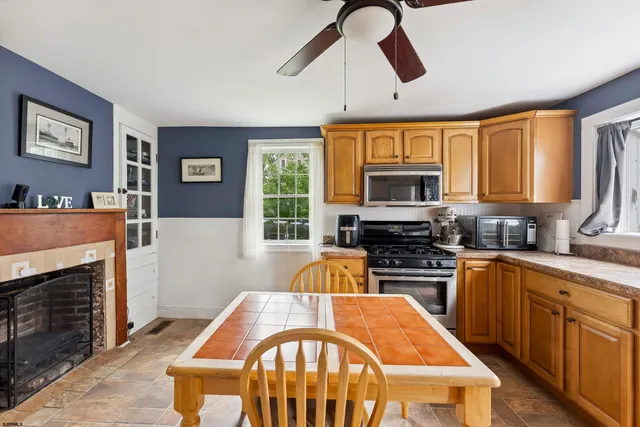 a kitchen with stainless steel appliances granite countertop a stove top oven a sink a dining table and chairs