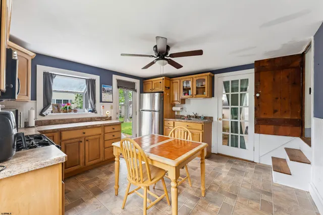 a kitchen with stainless steel appliances granite countertop a stove a sink dishwasher a dining table and chairs with wooden floor