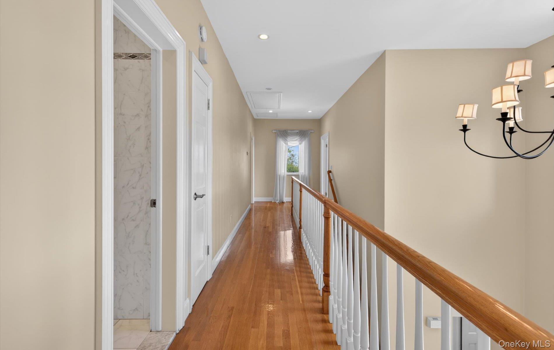 16 East Slope Road Bayville, NY 11709 - Photo 22 of 48 Upper-level hallway featuring wood-finish flooring, recessed lighting, a chandelier, and a white baluster railing with a wooden handrail