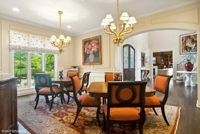 a view of a dining room with furniture a chandelier and large windows
