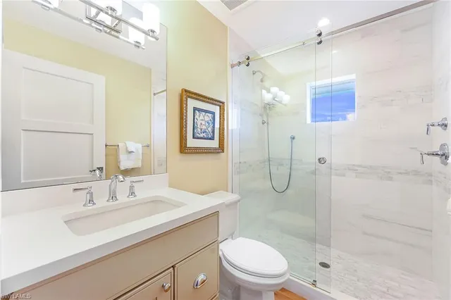 a bathroom with a shower sink vanity mirror and toilet