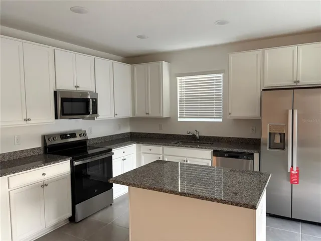 a kitchen with granite countertop a sink dishwasher stove and refrigerator with wooden floor