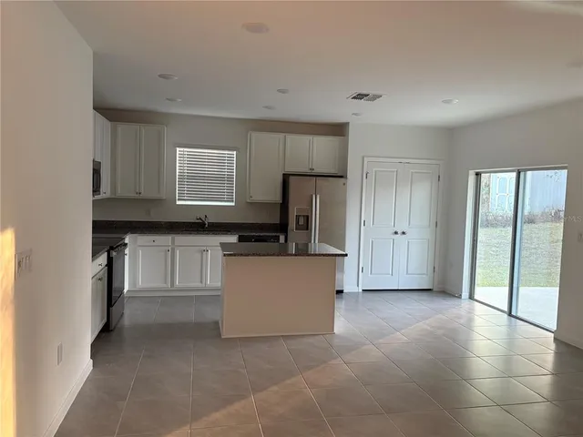 a large white kitchen with a sink and a refrigerator