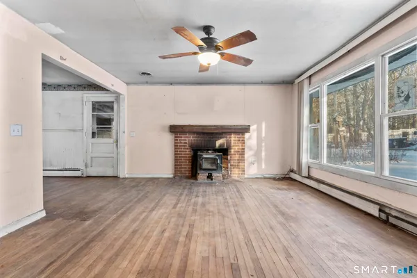 a view of empty room with wooden floor and fireplace