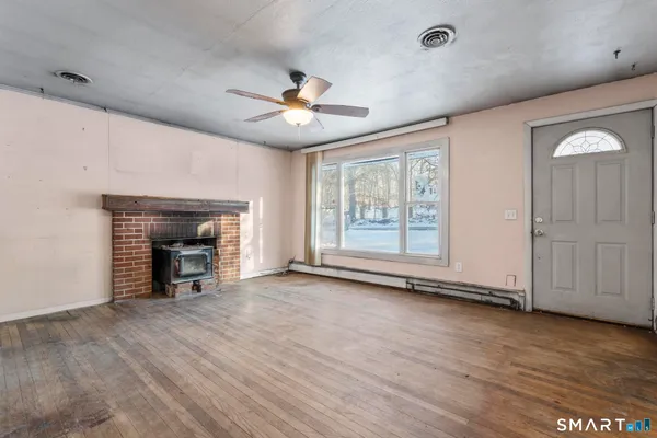 an empty room with wooden floor fireplace and windows