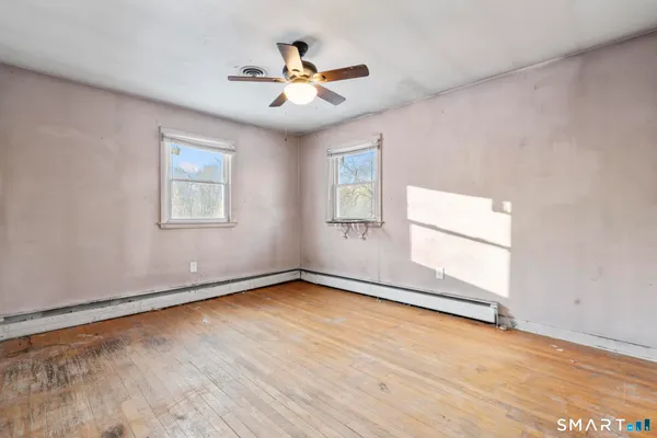 an empty room with wooden floor and windows