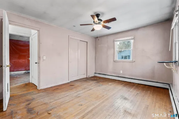 a view of an empty room with wooden floor and a window