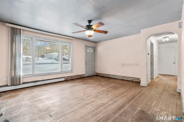 a view of an empty room with a window and wooden floor