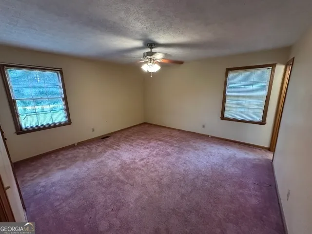 an empty room with windows and fan