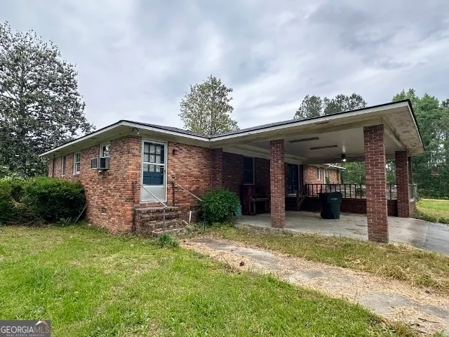 a view of a house with a small yard and a large tree