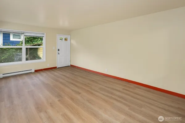 an empty room with wooden floor and windows