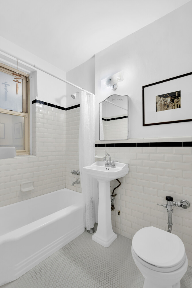 9425 Shore Road, Unit 1H Brooklyn, NY 11209 - Photo 5 of 10 a bathroom with a white bath tub a sink and a mirror